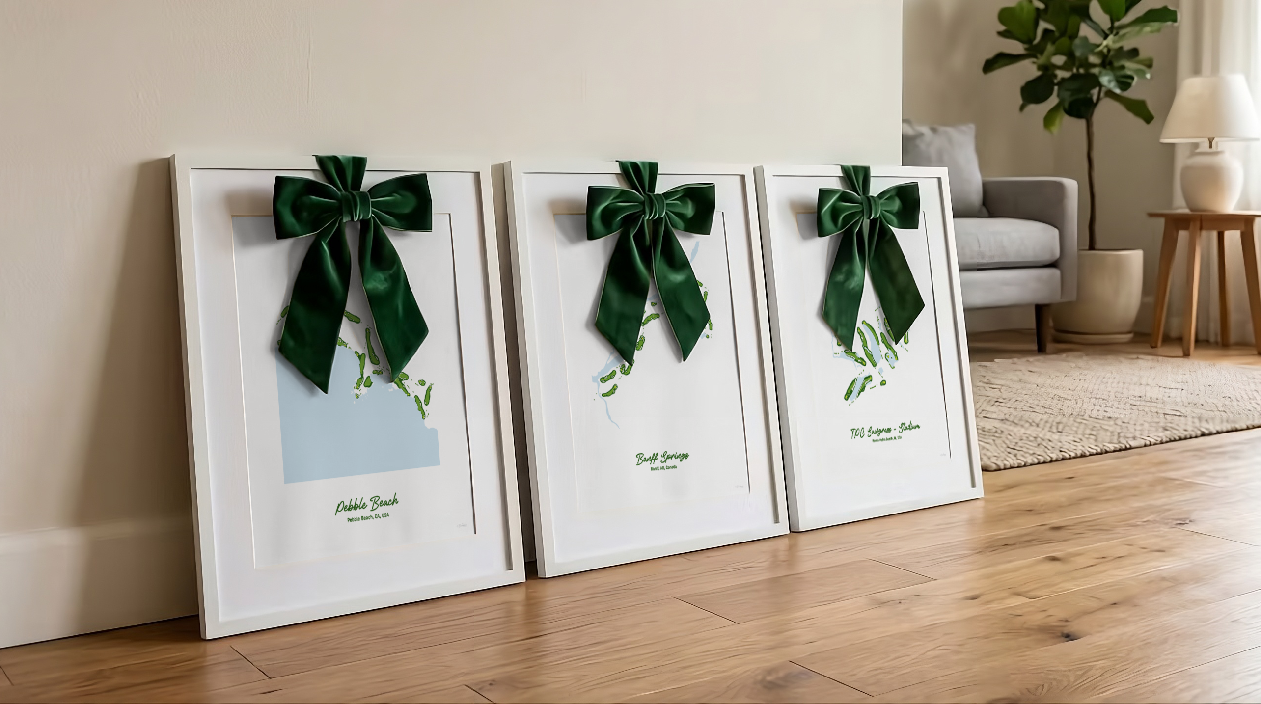 Three framed golf course prints with green ribbons on a wooden floor in a living room.